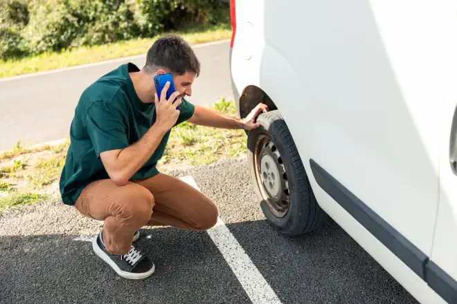 mobilny serwis TIR kiedy wezwać pomoc, mężczyzna patrzący na uszkodzone koło i dzwoniący do pomocy